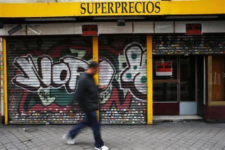 A man walks past a closed down business in Madrid March 27, 2013. REUTERS/Susana Vera